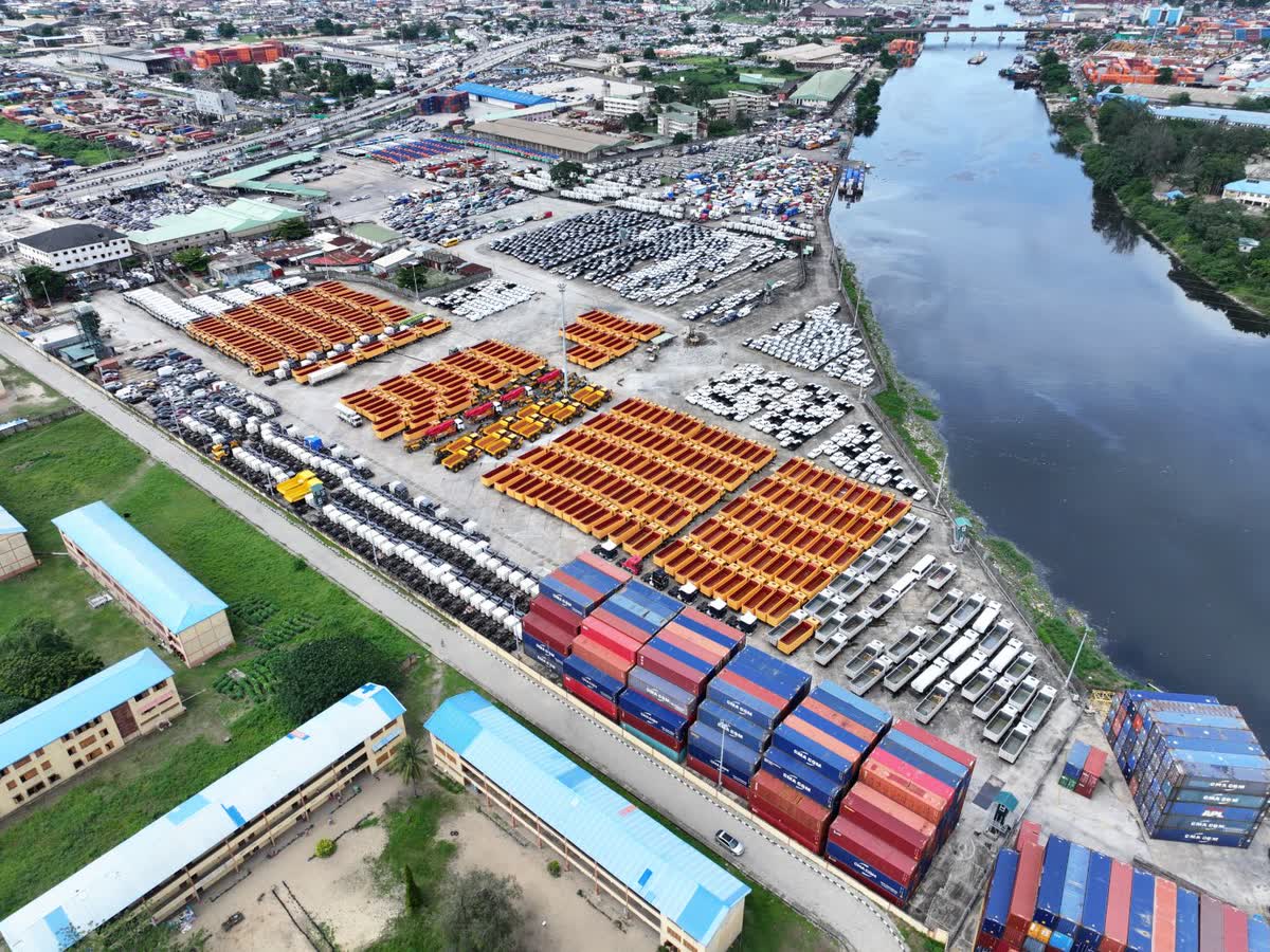 Aerial view of the PTML Mile 2 off-dock bonded terminal on the Lagos waterfront, with tipper bodies, vehicles and container stacks along the barge berths